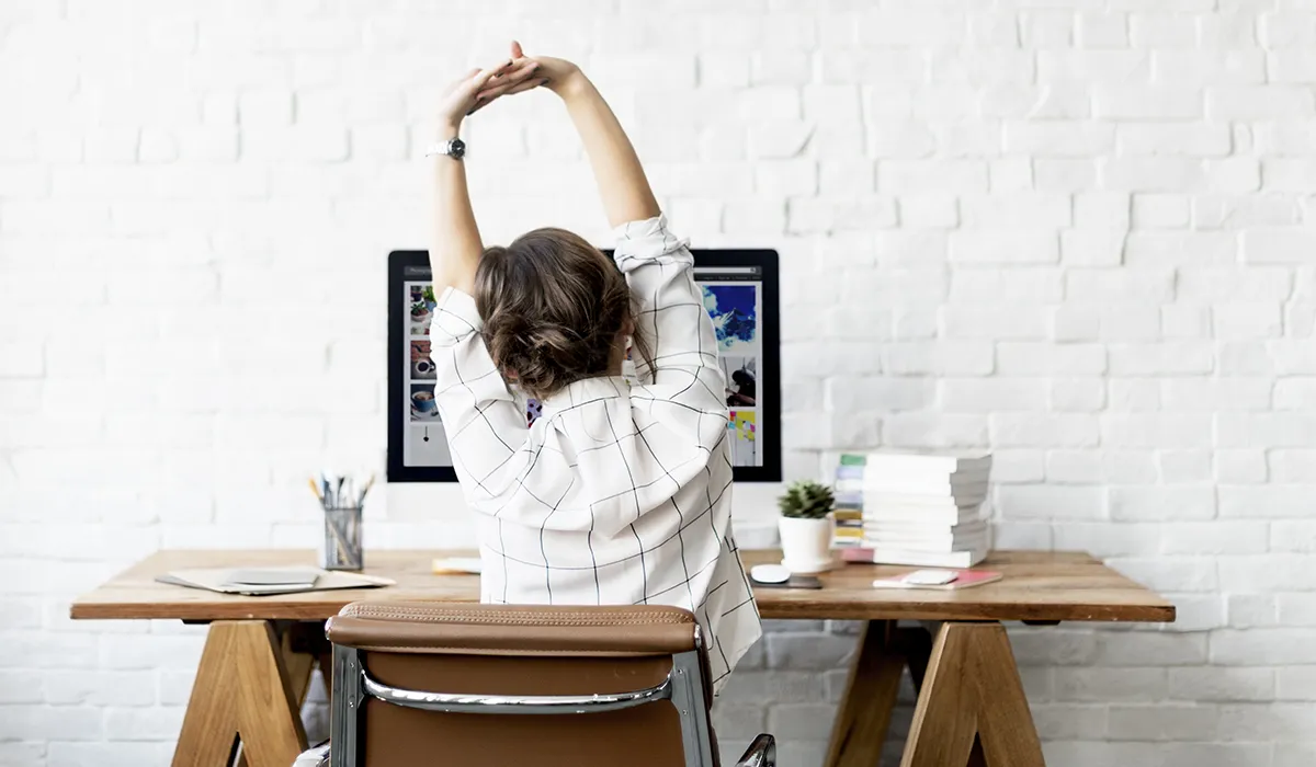 Person doing gentle desk stretches during a work break